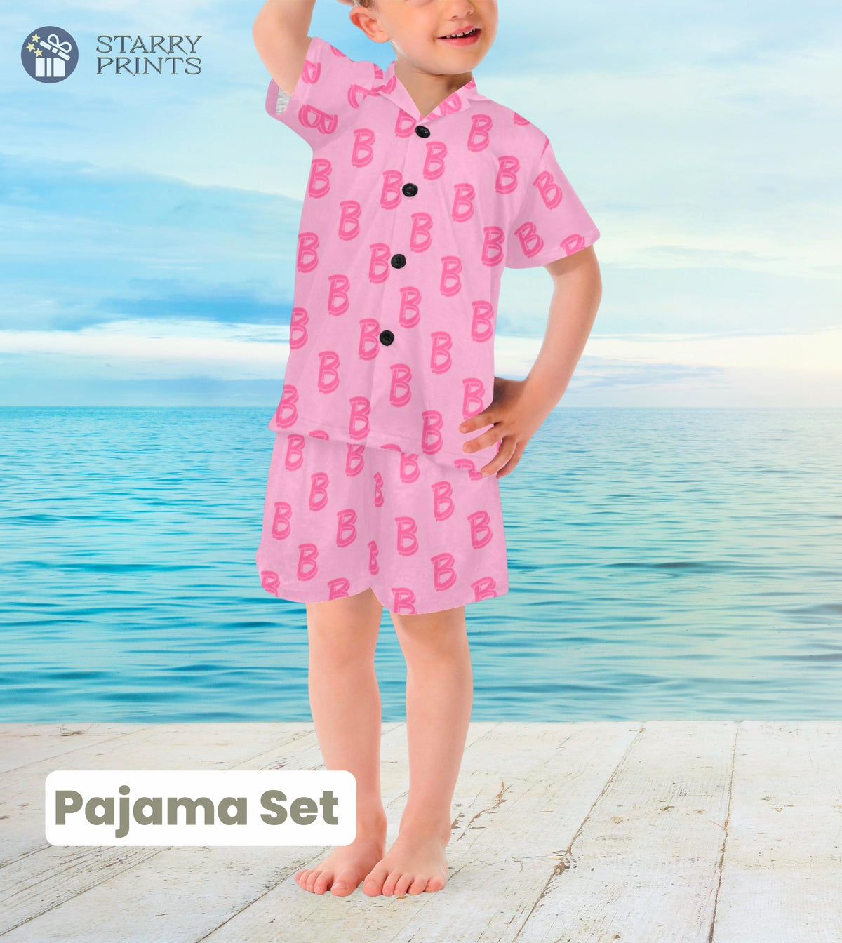 A toddler's pajama set featuring a pink top with the letter 'B' printed in a large font, paired with matching pink shorts. The design is inspired by Barbie's Ken, offering a playful and vibrant look for young kids.