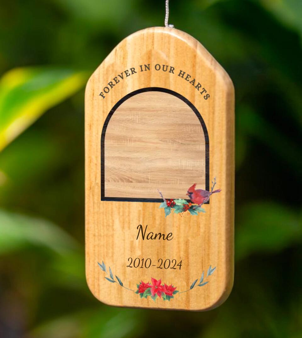 Personalized Memorial Wind Chime with Custom Photo, Metal and Wooden Remembrance Gift" - A wooden and metal wind chime with a personalized photo, hanging outside on a tree branch. A small bird and metal tubes hang below the photo, creating soothing chimes when the wind blows. A heartfelt way to remember a loved one.