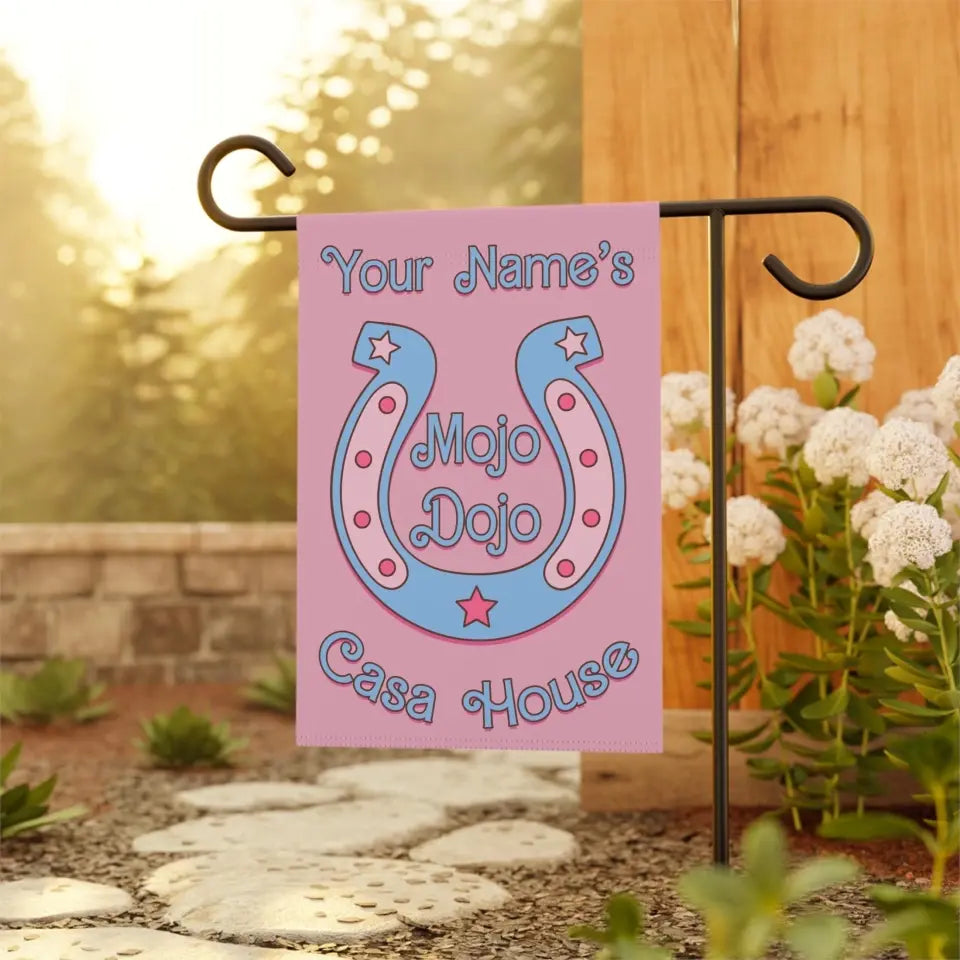 Pastel pink personalized garden flag with horseshoe design, featuring 'Mojo Dojo Casa' text and space for custom name. Barbiecore aesthetic with playful and colorful elements, symbolizing luck and individuality
