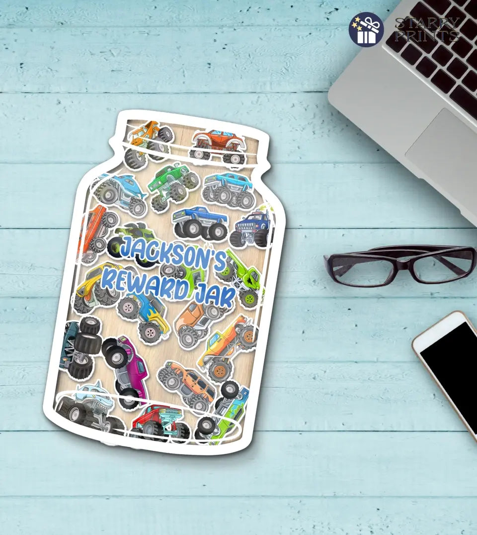 Clear acrylic reward jar filled with vibrant monster truck tokens, showcasing a customizable nameplate at the front. The jar is accompanied by a rustic wooden stand, emphasizing its premium quality and detailed design