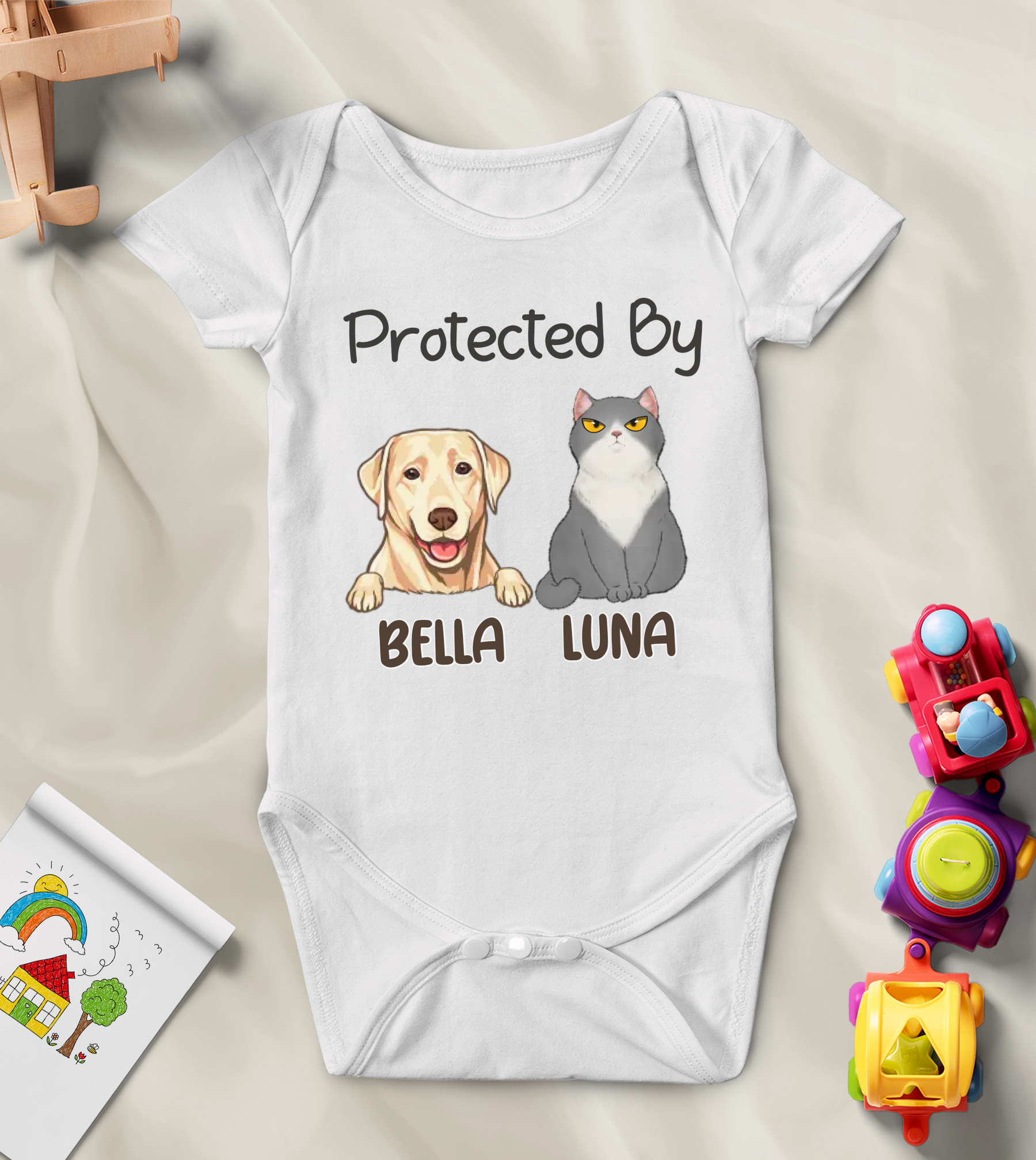 A white baby onesie with a quote "Protected by" followed by a portrait of a dog or cat and their name printed on it.